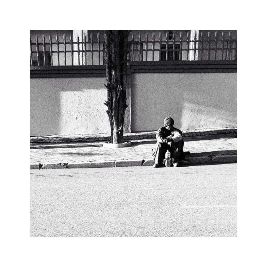 Man sitting on the sidewalk.