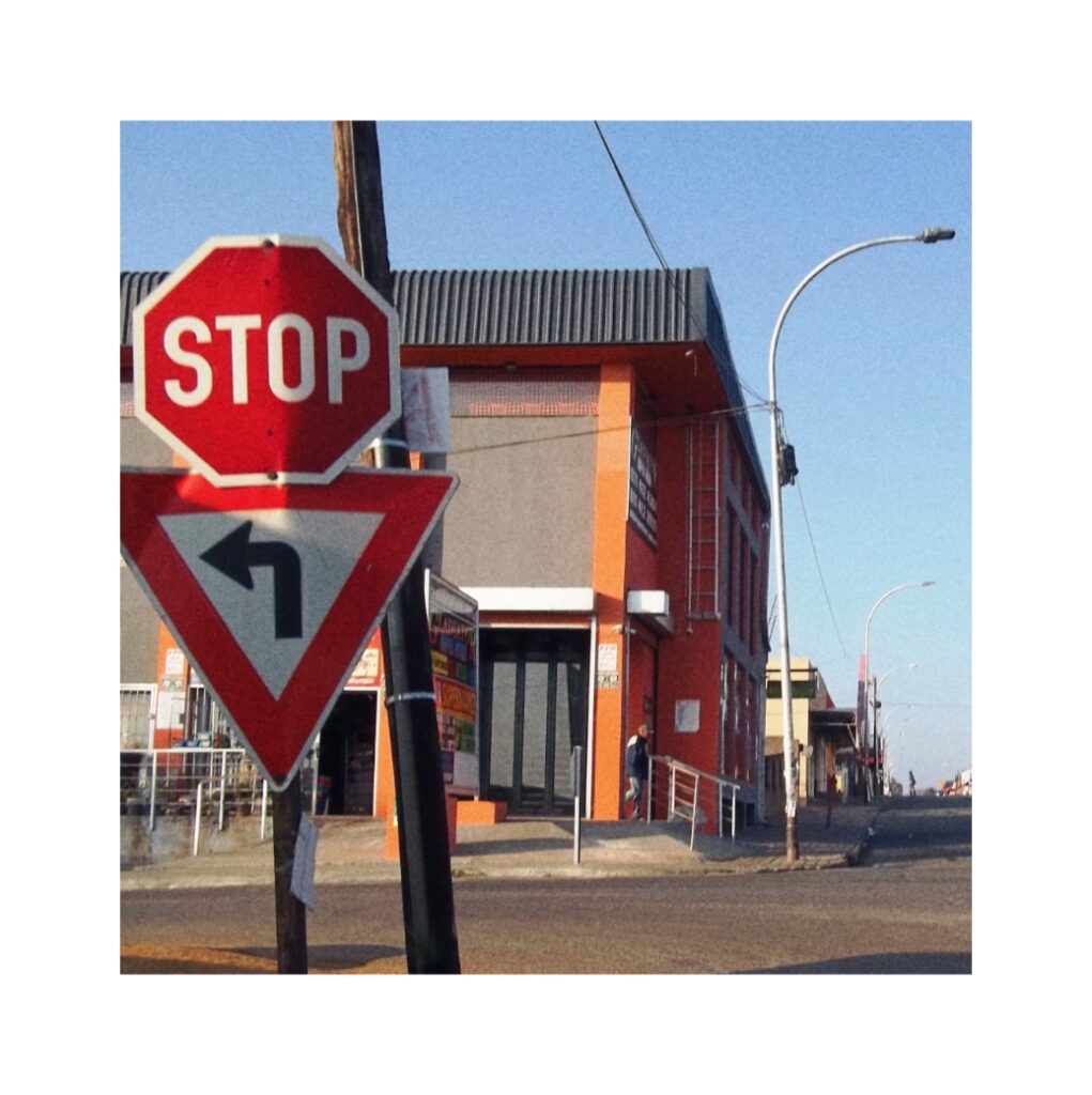 Two traffic signs in the foreground. In the background an orange building.