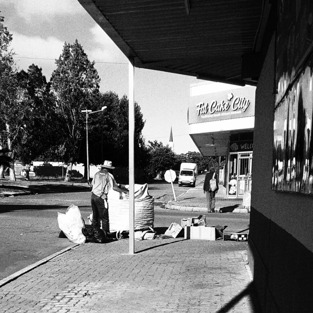 A man standing beside a bag full of boxes destined to be recycled.
