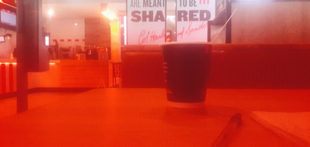 An image of a table and chairs within a fast food restaurant in the West of Gauteng. Part of the image is in red due to a filter in front of the camera lens.