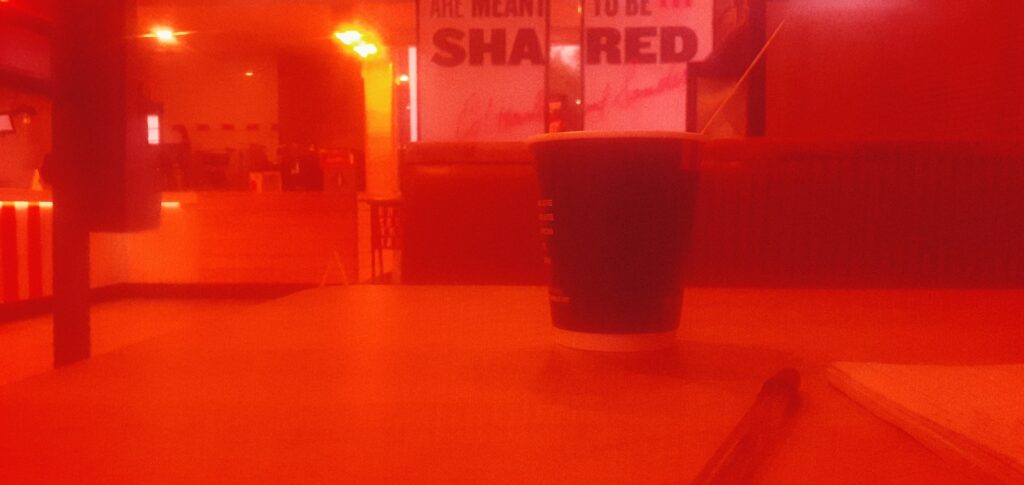 An image of a table and chairs within a fast food restaurant in the West of Gauteng. Part of the image is in red due to a filter in front of the camera lens.