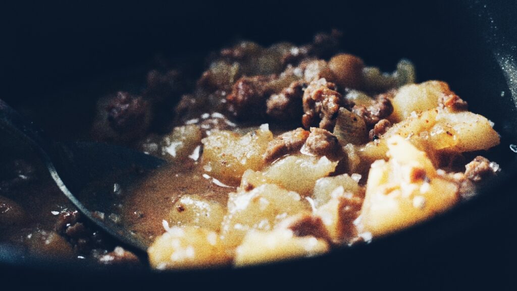 A photograph of a simple ground beef dish with potatoes and baked beans.