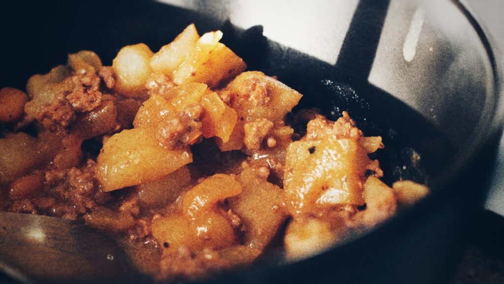 A photograph of a simple ground beef dish with potatoes and baked beans.