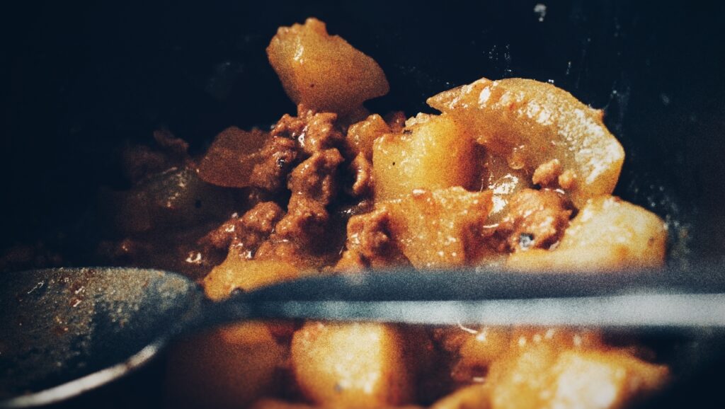 A photograph of a simple ground beef dish with potatoes and baked beans.