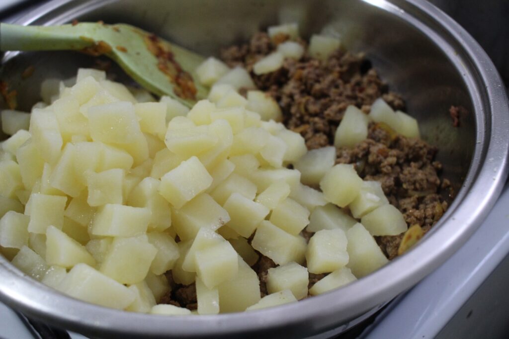 Boiled potatoes and ground beef in a pan.