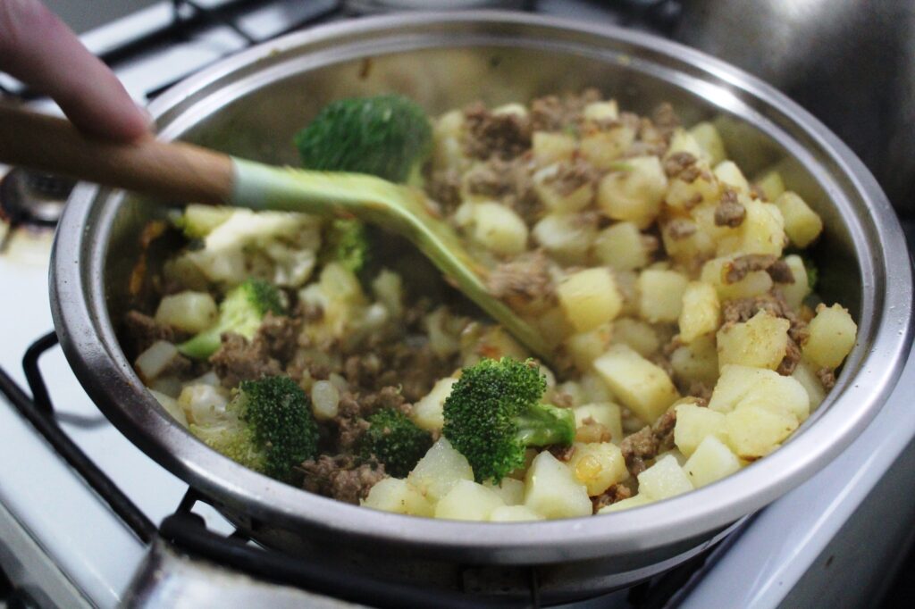 Broccoli in a pan along with cauliflower and ground beef.