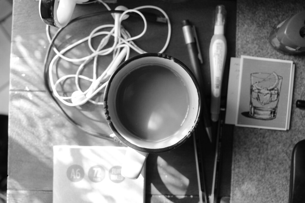 A messy table: a cup, earphones, pens, pencils.